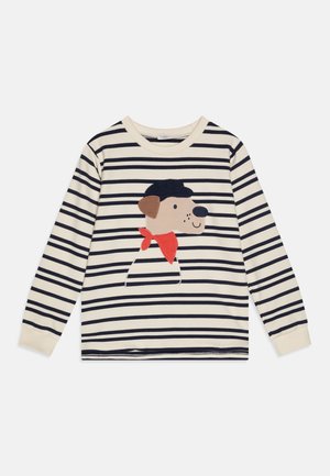 Chemise à manches longues crème et rayée bleu marine avec une application d'un chien souriant portant un chapeau noir et une écharpe rouge sur le devant.