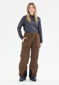 Bruine waterdichte skibroeken hebben een hoge taille met twee voorzakken, zwarte accenten aan de onderkant en een relaxte pasvorm voor bewegingsgemak.