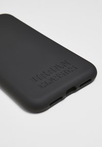 Coque de téléphone en silicone noir avec le texte "URBAN CLASSICS" en relief, texture lisse, découpes précises pour les ports et coins arrondis.