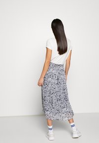 Sukně midi délky s květinovým potiskem v námořnické modré a bílé barvě, vyrobená z lehké tkaniny. Disponuje elastickým pasem a volným střihem.