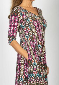 Färggklad klänning med ett geometriskt diamantsmönster i rosa, blått, brunt och vitt. V-ringning och trekvartsärmar med sidofickor.