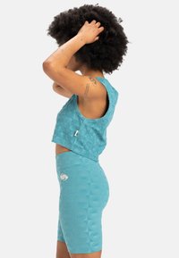 Teal crop top and shorts set featuring textured geometric patterns, ribbed material, and a logo accent on the shorts.