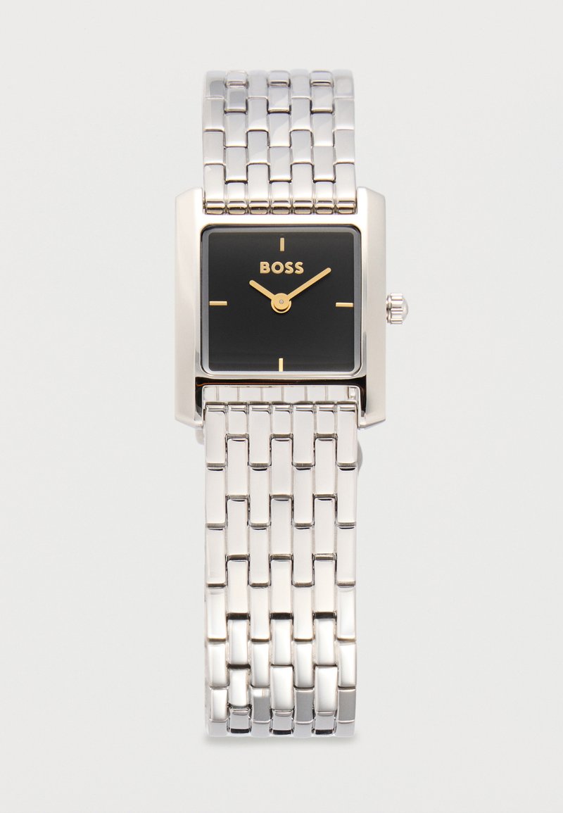 Hõbedast lingiga käekell ristkülikukujulise musta sihverplaadiga, kuldsete osutitega, minimalistlike tunniindikaatoritega ja "BOSS" logo kellal 12 asukohas.