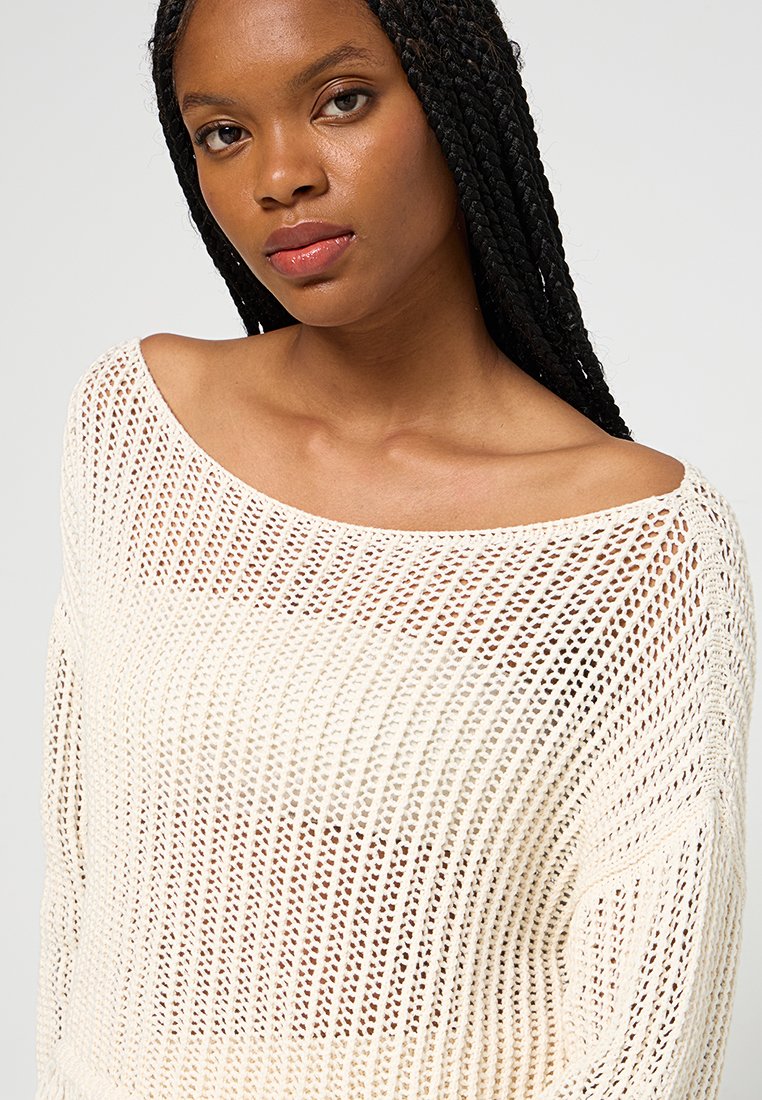 Maglione lavorato a maglia off-white con una vestibilità oversize, caratterizzato da un ampio scollo a barca e una trama aperta e morbida.