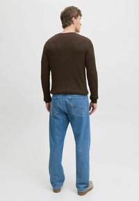 Pulover ribbed maro cu mâneci lungi, asortat cu blugi din denim de un albastru deschis. Outfit-ul are o croială confortabilă și un decolteu rotund.
