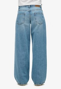 Jasnoniebieskie dżinsowe spodnie w szerokim kroju z wysokim stanem, dwoma tylnymi kieszeniami oraz dołem z lekko marszczonym wykończeniem. Klasyczny krój pięciokieszeniowy.