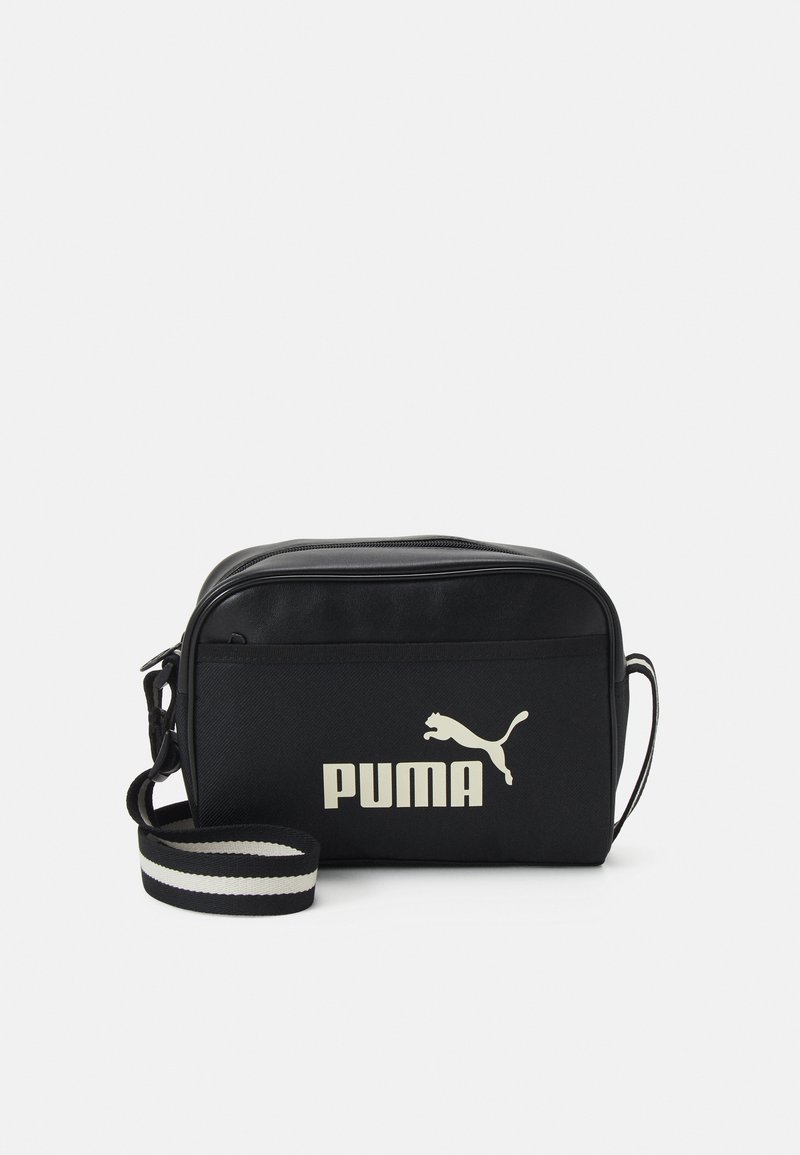 Schwarze Polyester-Crossbody-Tasche mit einem Reißverschluss, einem gestreiften Tragegurt und einem großen weißen Puma-Logo auf der Vorderseite.