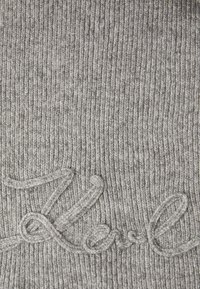 Bonnet en tricot côtelé gris avec un « Z » brodé en fil gris clair, présentant un tissu doux et texturé.