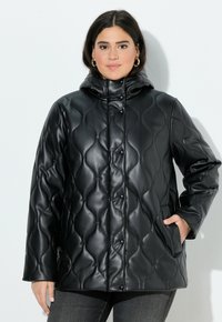 Cappotto imbottito nero in materiali sintetici, con colletto alto, chiusura a bottoni a pressione e tasche laterali. Texture liscia e lucida.
