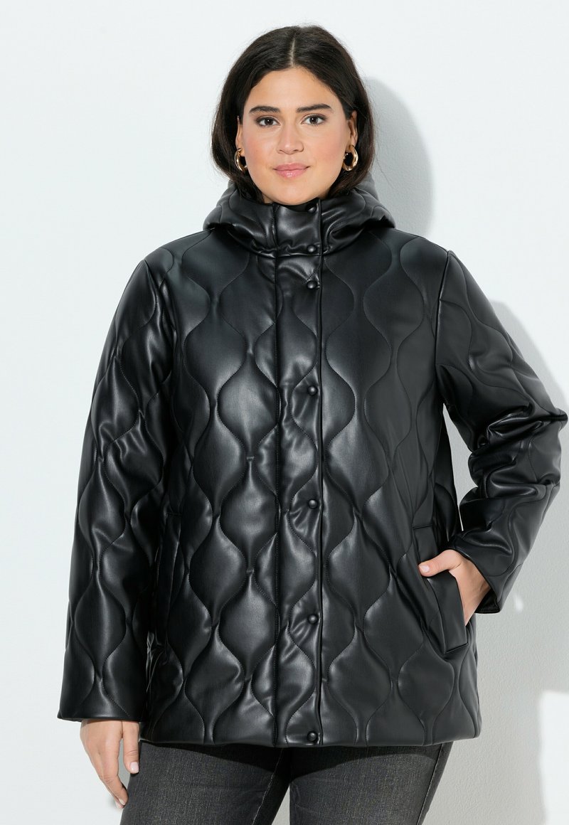 Cappotto imbottito nero in materiali sintetici, con colletto alto, chiusura a bottoni a pressione e tasche laterali. Texture liscia e lucida.
