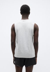 Ανοιχτό γκρι αμάνικο πουκάμισο από βαμβάκι. Απλός σχεδιασμός με στρογγυλή λαιμόκοψη χωρίς γραφικά στοιχεία, συνδυασμένο με μαύρο σορτς.