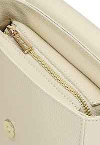 Crème-kleurige leren tas met een gestructureerd oppervlak, voorzien van een gouden rits en hardware. Het interieur is gevoerd met een zachte stof.