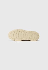 Rubber shoe sole with a textured tread pattern in light beige, featuring prominent grooves and branding near the heel. Smooth finish overall.