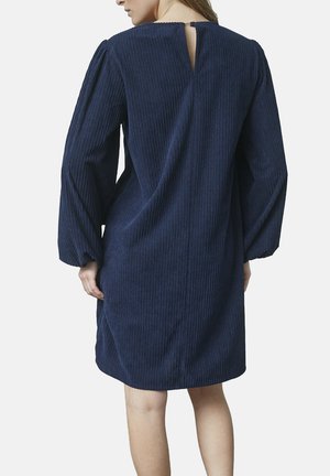 Marineblå kordfløjls kjole med lange ærmer, en nøglehul detalje på ryggen og en afslappet pasform med lodret ribbet tekstur.