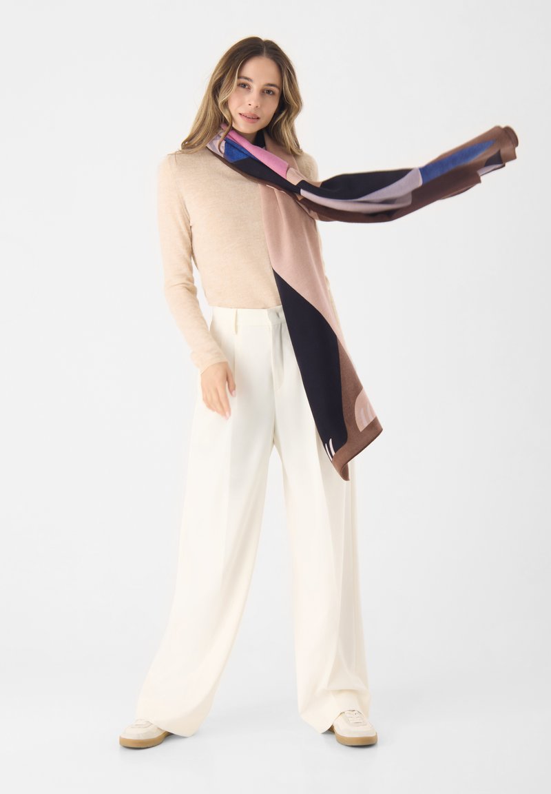 Multicolore sjaal van zachte stof, met geometrische patronen in tinten bruin, roze, marineblauw en lichtblauw. De randen zijn lichtjes rafelig.