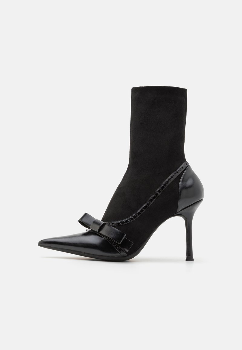 Melnas potītes zābaki ar smailu purngalu, izgatavoti no zamša un ādas. Ar lenti akcentu un stiletto papēdi. Gludas un teksturētas virsmas.