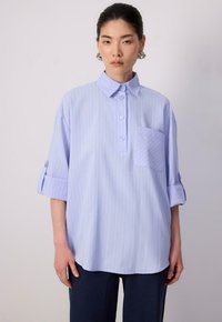 Cămașă cu dungi albastre deschise, realizată dintr-un material moale, având un guler, mâneci scurte împăturite, închidere cu butoane și un buzunar pe piept.