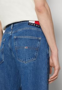 Blå denimjeans med rak passform, utrustade med två bakfickor, en märkt midjemärkslapp i rött, vitt och blått samt kontrasterande sömmar.