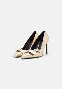 Metallic gold high-heeled shoes with pointed toes, featuring a glossy finish and silver buckle accents on the front. Black inner lining.
