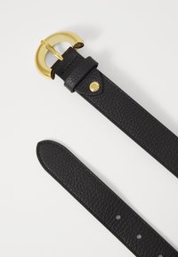 Ceinture en cuir noir avec une finition texturée, dotée d'une boucle circulaire en ton doré et d'un détail à pression près de la boucle.