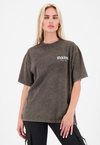 Oversized, kortlopende T-shirt in donkergrijs met een vintage wasstructuur. Heeft witte bedrukte branding op de linkerborst.