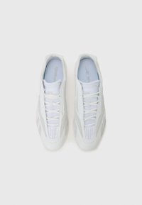 Adidași albi sport cu un material neted, închidere cu șireturi, guler căptușit și accente texturate pe laterale și vârfuri.