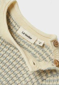 Pull en tricot texturé crème et gris pour bébé avec des boutons en bois et étiquette de la marque Lil' Atelier, taille 1-2 mois présentée.
