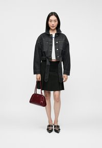 Jachetă din denim închis, cu croială scurtă și închidere cu nasturi, bluză albă scurtă, fustă neagră și poșetă lucioasă bordou. Sandale negre cu curele la glezne.