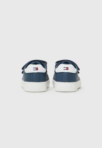 Mørkeblå lær-sneakers med hvite såler, med borrelåsrem, rund tå og en liten logo på hælen.