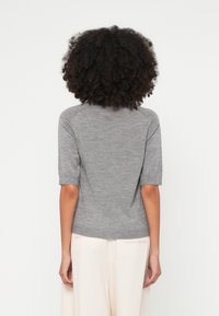 Hall hõlmikuga lühikeste varrukatega kootud kampsun ümmarguse kaelusega ja veidi lahtise lõikega. Sile tekstuur ja soonikservad; tagaosas peen õmblusdetail.