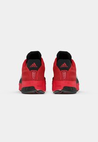 Red and black running shoes featuring a breathable mesh upper, textured accents, and a curved sole design with visible cushioning elements.