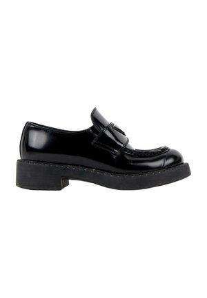 Mocassin en cuir verni noir avec semelle en caoutchouc épaisse et bride décorative sur le dessus, vu du côté gauche sur fond blanc.