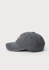 Donkergrijze pet gemaakt van denimstof. Beschikt over een gebogen rand, gestikte panelen en geborduurde letters aan de voorkant. Zachte textuur, casual ontwerp.