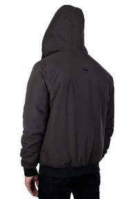 Giacca a hood grigio scuro con zip frontale, polsini ed elasticità in vita. Texture liscia con un design semplice e un branding minimo. Vista posteriore.