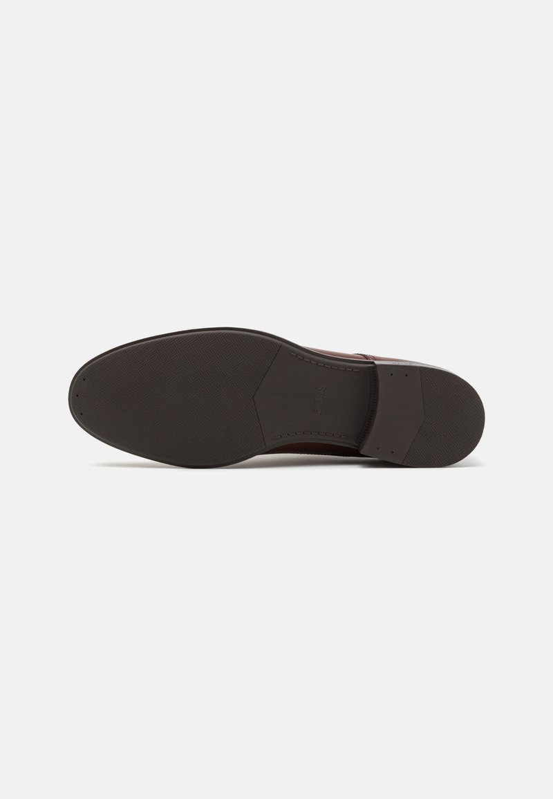 Brown leather shoe sole with a smooth finish, rubber traction pattern, and subtle branding. Features a classic shape with rounded toe.