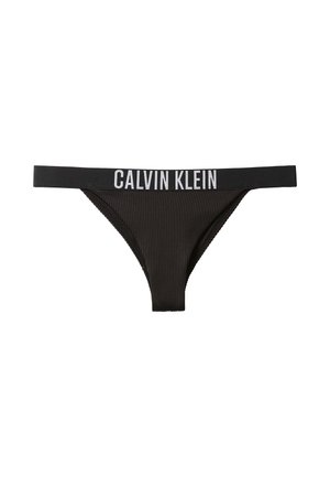 Schwarzer, gerippter String mit breitem elastischem Bund, auf dem der weiße Schriftzug "Calvin Klein" prangt.