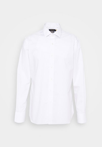 Chemise blanche à boutons, à manches longues, avec un col standard et une patte de boutonnage dotée de boutons beiges. Tissu lisse avec une coupe ajustée.