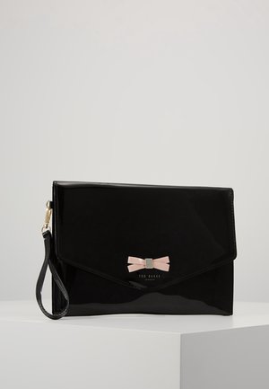 Czarna błyszcząca kopertówka z różową kokardą, paskiem na nadgarstek i logo Ted Baker London umieszczona na białej powierzchni.