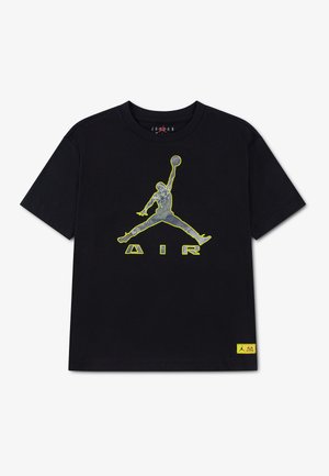 T-shirt noir avec grand logo Jumpman cerné de jaune et texte AIR sur la poitrine ; petite étiquette jaune près de l’ourlet. Aucune personne visible.