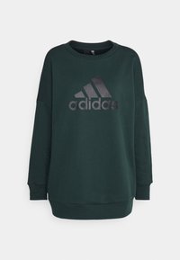 Sudadera verde hecha de una mezcla de algodón. Presenta un escote redondo, hombros caídos y un logo negro de Adidas impreso en la parte frontal.