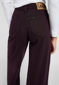 Bordeauxfarbene Weite-Leg-Jeans aus robustem Denim, mit einem Lederetikett am Bund und zwei Gesäßtaschen mit geschwungener Naht.