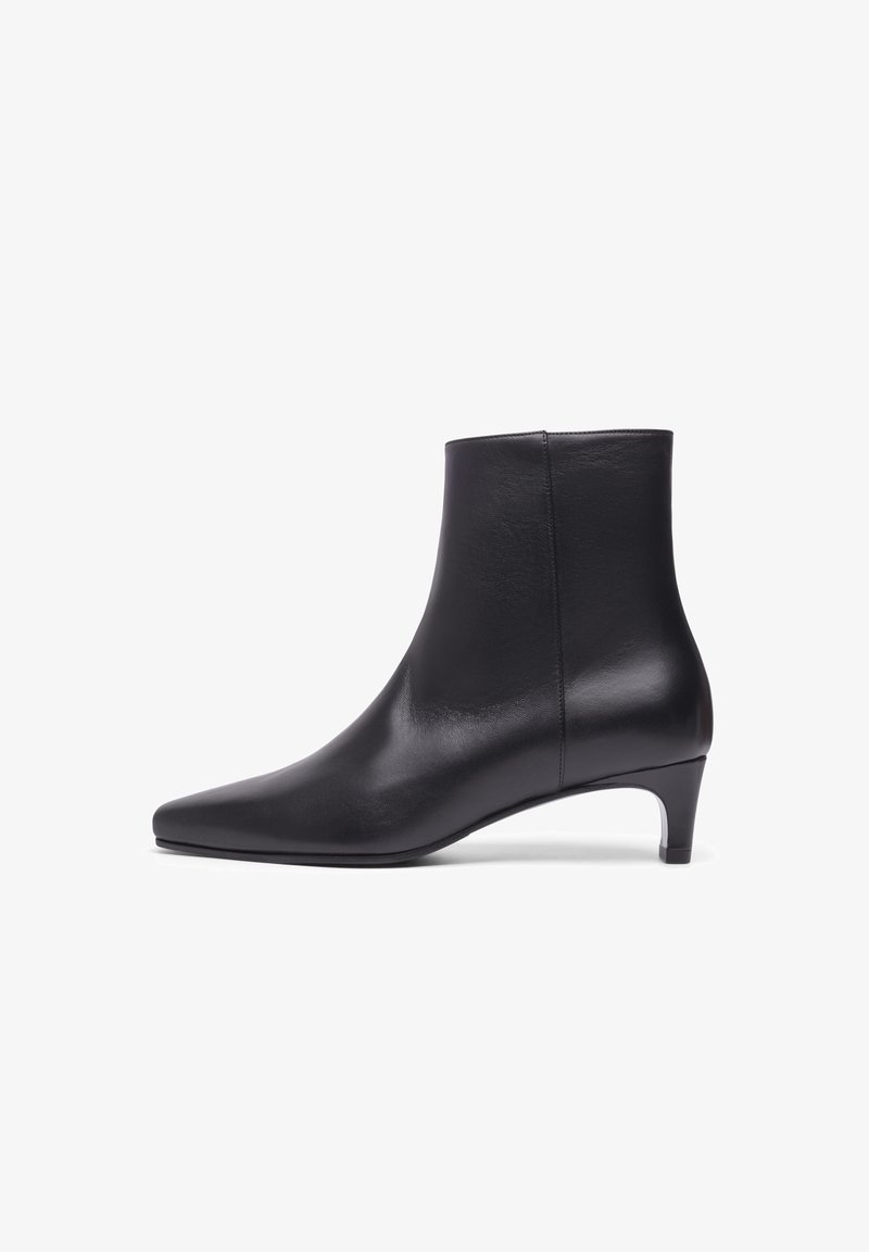 Bottines en cuir noir avec un bout pointu, texture lisse et un talon modeste, présentant un design épuré sans quincaillerie ni accents visibles.