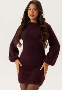 Burgundy stickad klänning med en mjuk, lurvig textur, som har långa, ballongärmar och en figurnära silhuett, som slutar ovanför mitten av låret.