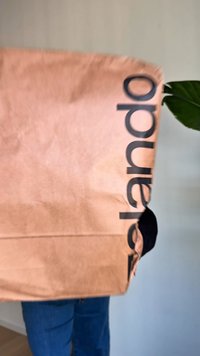 Rjava papirnata nakupovalna vrečka z velikim črnim napisom "zalando." Gladek tekstura, pravokotna oblika in nežno naguban površina.