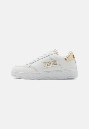 Baskets en cuir blanc avec une finition texturée, présentant un talon rehaussé de doré, une patch logo et une semelle en caoutchouc à motifs.