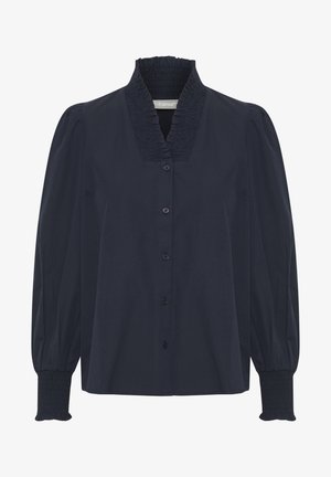 Námořnická modrá blůza na knoflíky se smockovaným límcem, dlouhými nafouknutými rukávy a smockovanými manžetami. Vyrobena z hladké látky se strukturovaným designem.