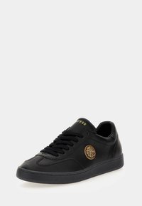 Sneaker nere in pelle con lacci neri, colletto imbottito e emblema di leone dorato. Texture liscia e suola in gomma con cuciture a contrasto.