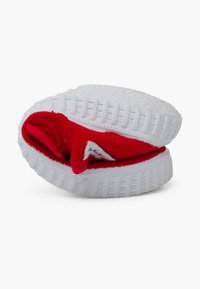 Adidași roșii moi cu interior căptușit, talpă exterioară din cauciuc texturat alb, detalii cusute și un mic eticheta cu un design colorat.