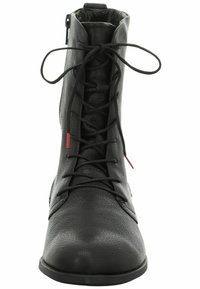 Bottine en cuir noir avec une finition texturée, dotée d'un laçage à l'avant, d'une fermeture éclair sur le côté et d'accents rouges contrastants.