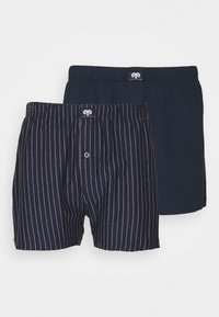 Deux paires de boxers pour hommes : l'une en bleu marine uni, l'autre avec des rayures verticales rouges fines sur fond bleu marine. Les deux présentent une taille élastique et un bouton d'ouverture.